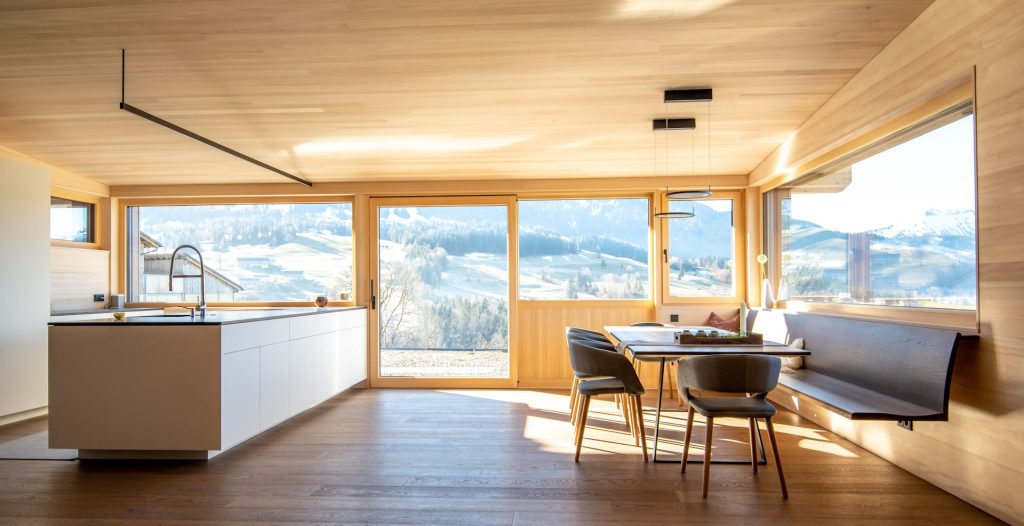 Cuisine et salle à manger dans une maison à ossature bois avec vue sur les Alpes.